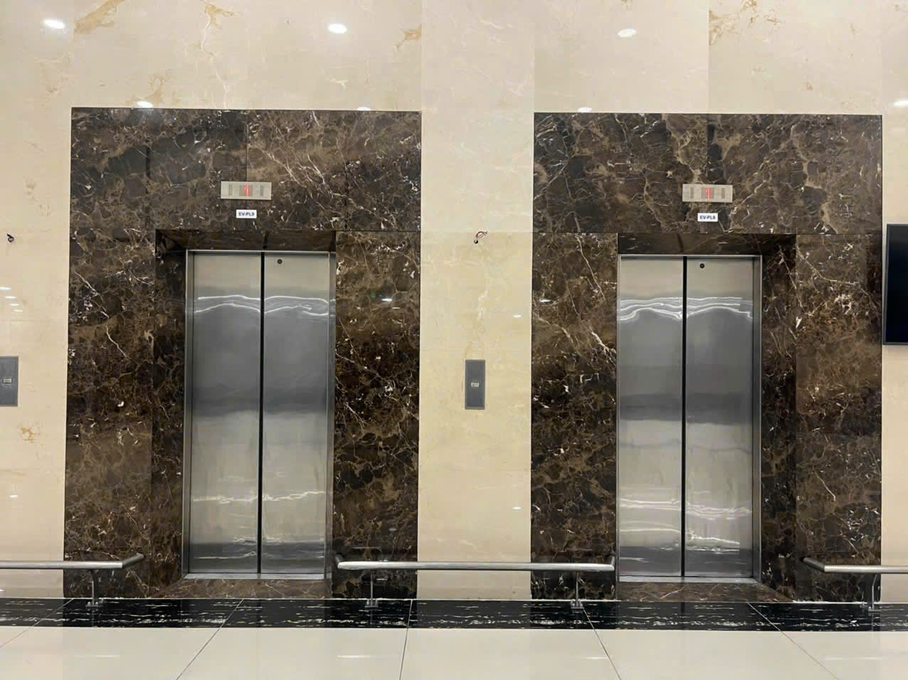 Hai thang máy cửa inox trong sảnh tòa nhà ốp đá marble nâu sang trọng